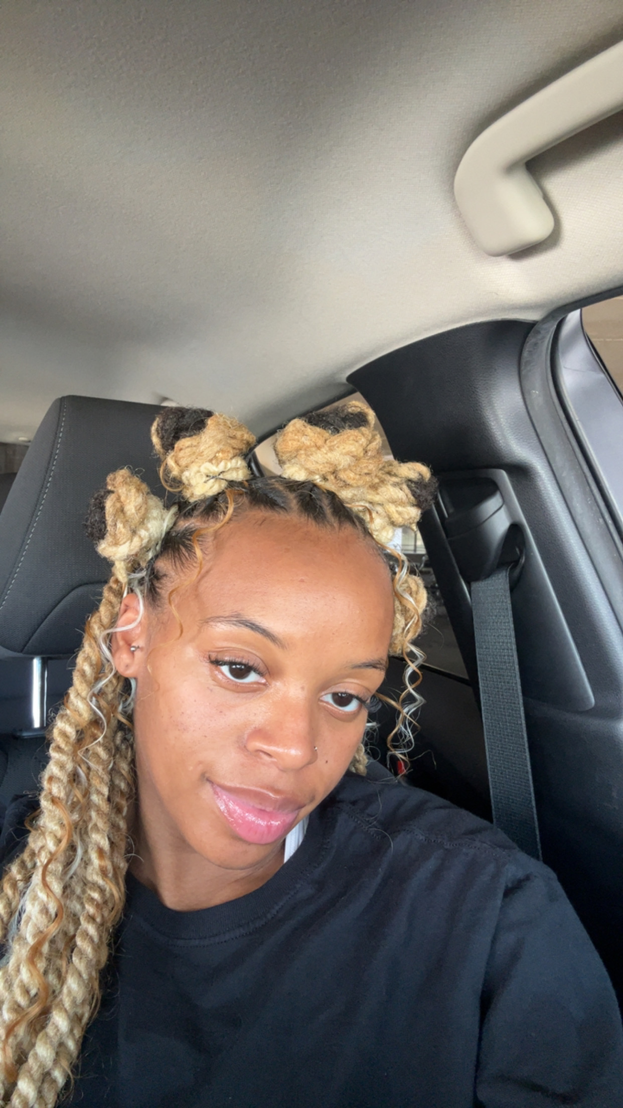 Client with honey-blonde locs styled into two looped top knots, the curled lengths left down