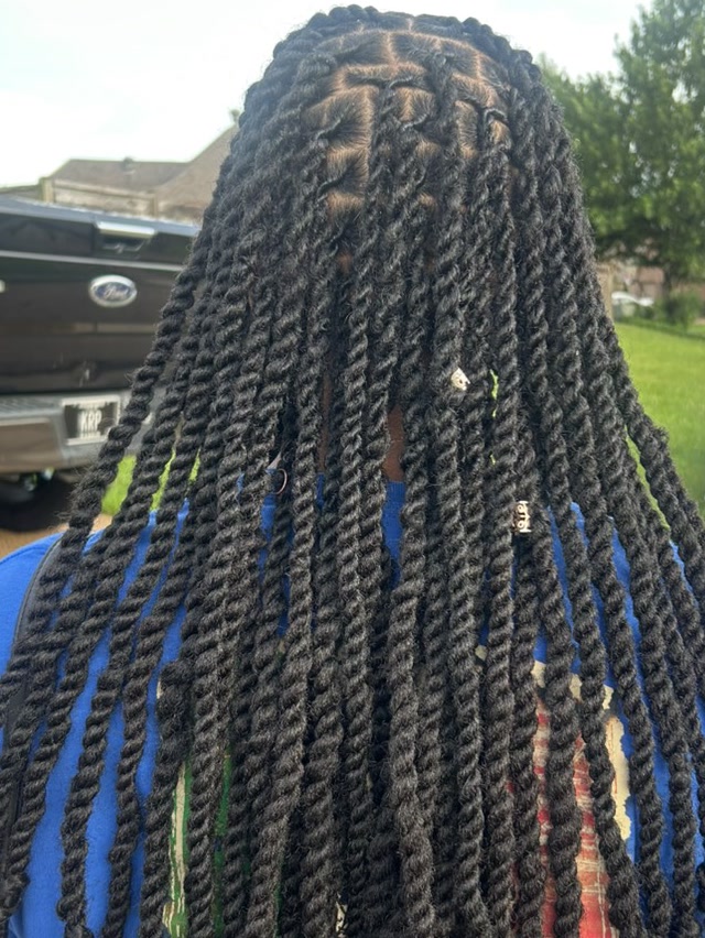 Back view of long two-strand twists installed over locs, falling to mid-back in even rows with a few beads set into the lengths